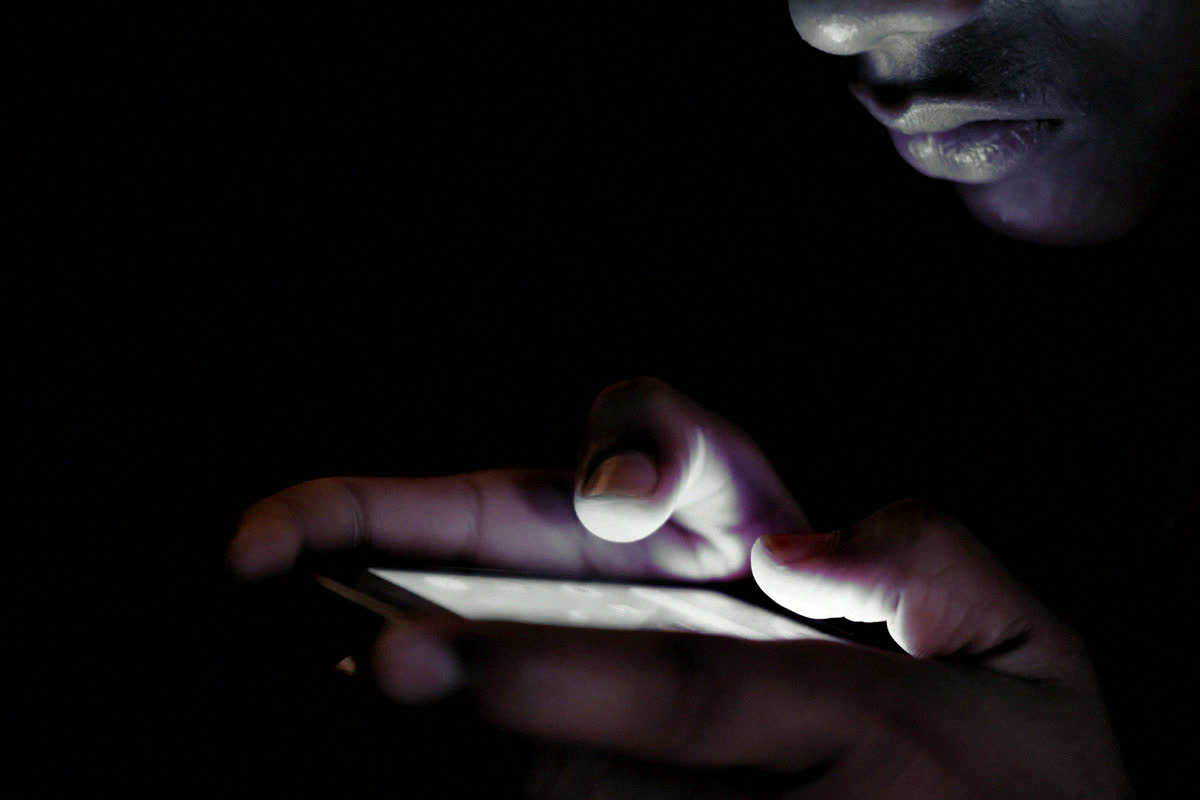 Manos escribiendo en un teléfono de noche
